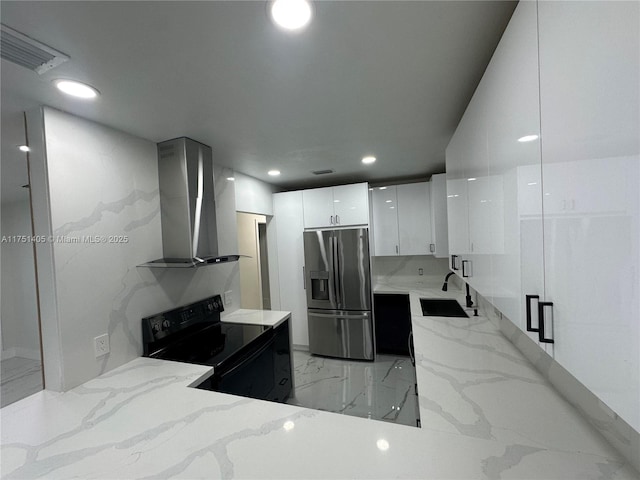 kitchen featuring white cabinetry, black electric range oven, wall chimney exhaust hood, modern cabinets, and stainless steel fridge