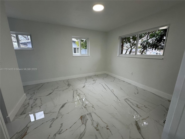 spare room with marble finish floor and baseboards