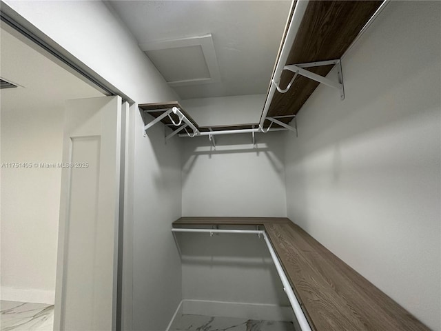 walk in closet with marble finish floor and attic access