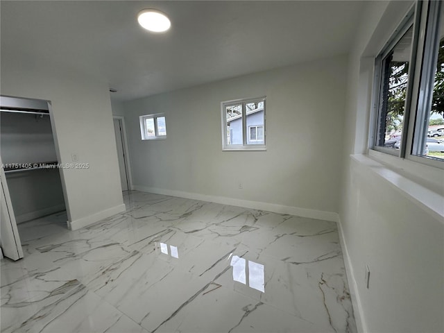 unfurnished bedroom with marble finish floor and baseboards