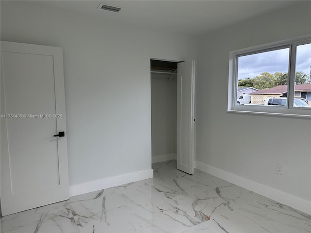 unfurnished bedroom featuring a closet, marble finish floor, visible vents, and baseboards