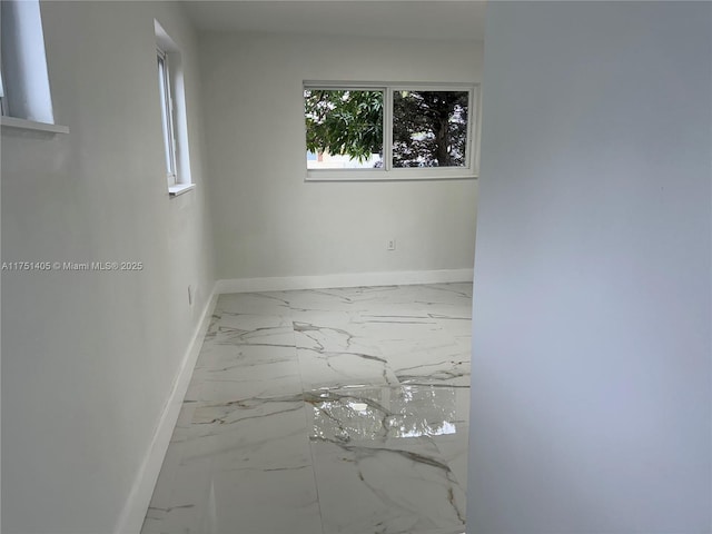 unfurnished room featuring marble finish floor and baseboards