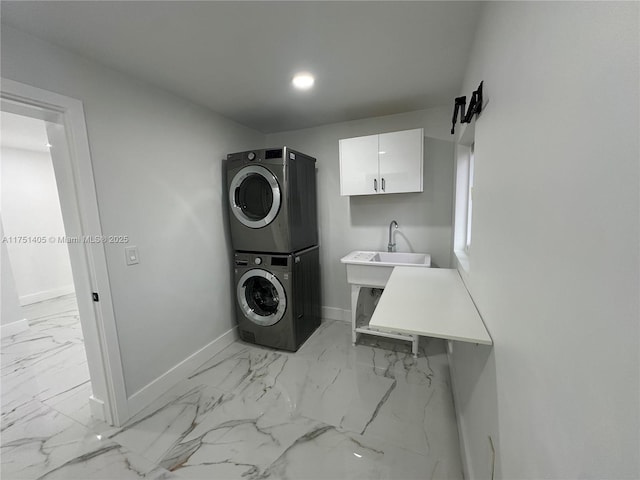 clothes washing area featuring baseboards, marble finish floor, a sink, and stacked washer / drying machine