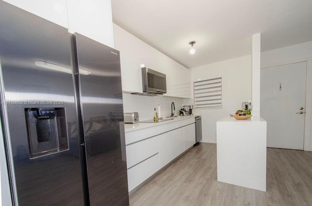 kitchen with light countertops, appliances with stainless steel finishes, light wood-style floors, white cabinetry, and modern cabinets