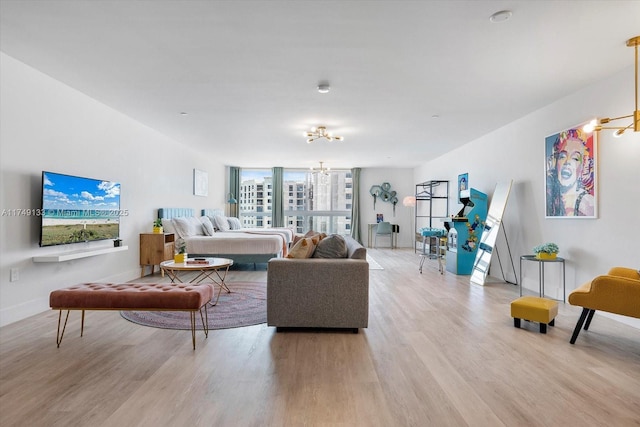 living area featuring light wood-style floors, baseboards, and an inviting chandelier