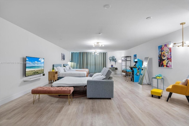 living area featuring light wood-style flooring, a chandelier, and baseboards