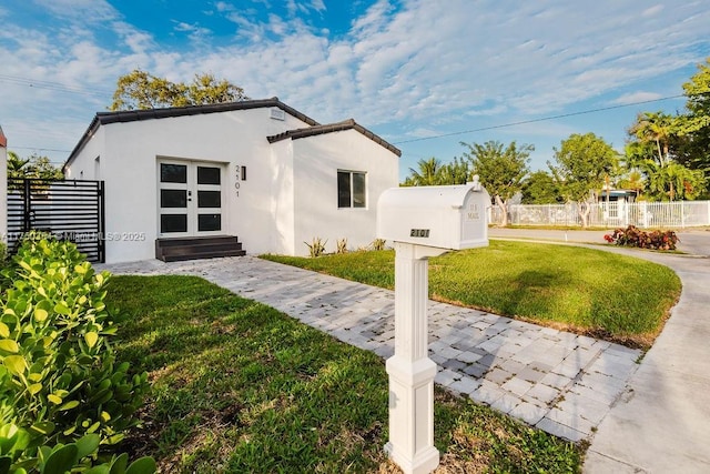 view of front of property featuring a front lawn, fence, and stucco siding