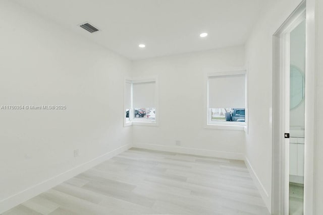 empty room with light wood-style floors, recessed lighting, visible vents, and baseboards