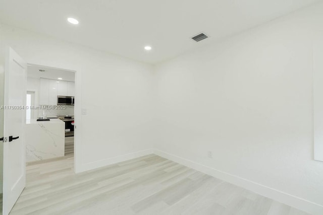 unfurnished room featuring light wood-style floors, recessed lighting, visible vents, and baseboards