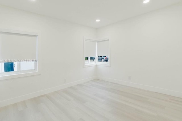 empty room with light wood-style flooring, baseboards, and recessed lighting