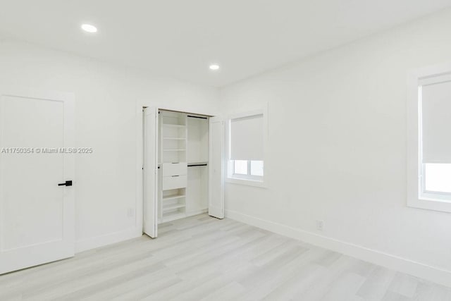 unfurnished bedroom featuring light wood finished floors, multiple windows, baseboards, and recessed lighting