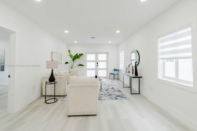 living area with recessed lighting, french doors, baseboards, and light wood finished floors