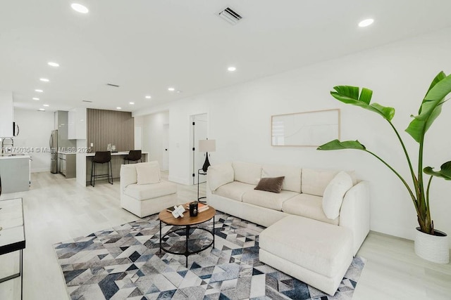 living room with visible vents, baseboards, light wood-style flooring, and recessed lighting