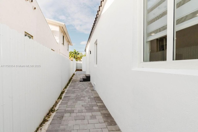 view of side of home with fence and stucco siding