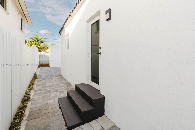 view of side of home with fence private yard, stucco siding, a patio, and entry steps