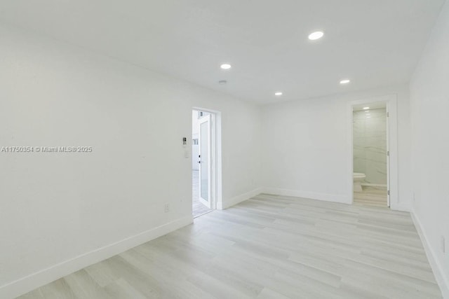 spare room featuring light wood-type flooring, baseboards, and recessed lighting