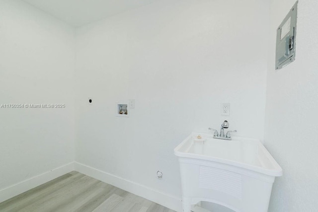 washroom with laundry area, baseboards, light wood-style flooring, hookup for a washing machine, and a sink