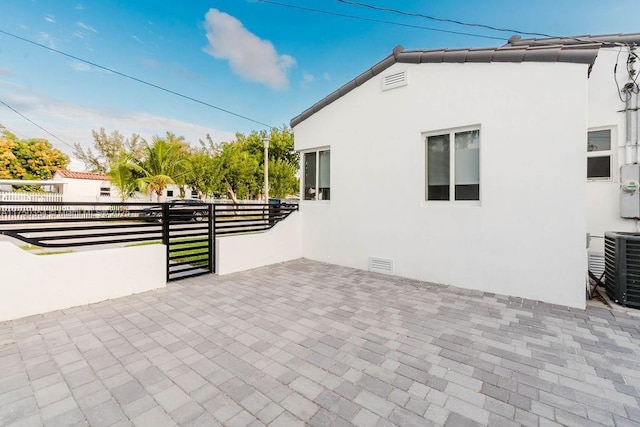 view of property exterior with a patio, stucco siding, central AC unit, crawl space, and fence