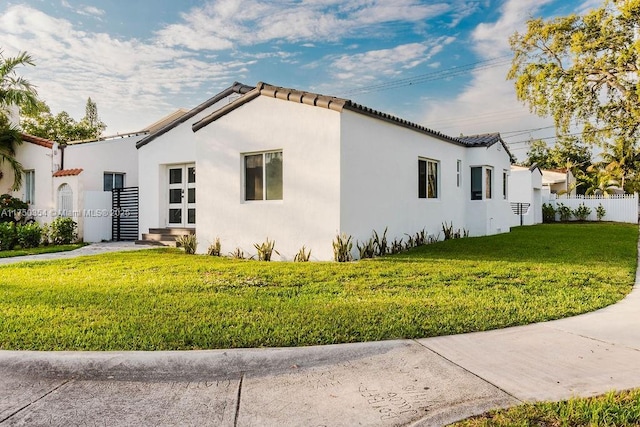 view of side of property with stucco siding, a tiled roof, and a yard