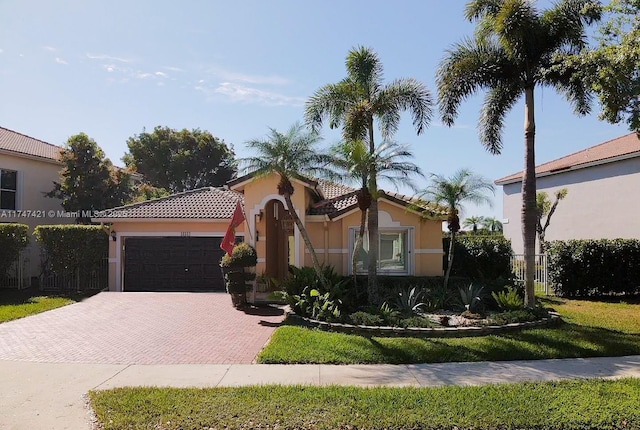 mediterranean / spanish house featuring decorative driveway, an attached garage, a tile roof, and stucco siding