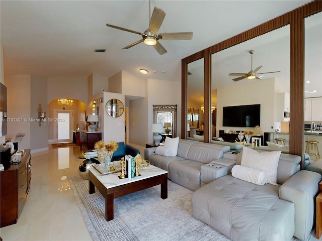 living room featuring arched walkways, light tile patterned flooring, visible vents, a ceiling fan, and vaulted ceiling