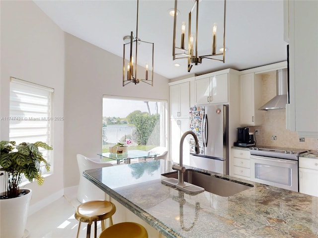 kitchen featuring tasteful backsplash, wall chimney exhaust hood, a kitchen breakfast bar, stainless steel appliances, and a sink