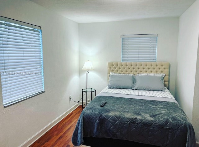 bedroom with dark wood finished floors and baseboards