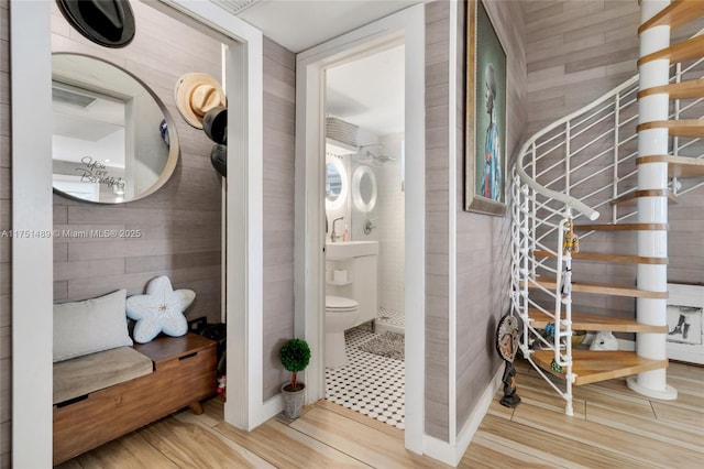 bathroom with wooden walls, toilet, and wood finished floors