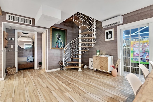 interior space with wood finish floors, a wall unit AC, and visible vents