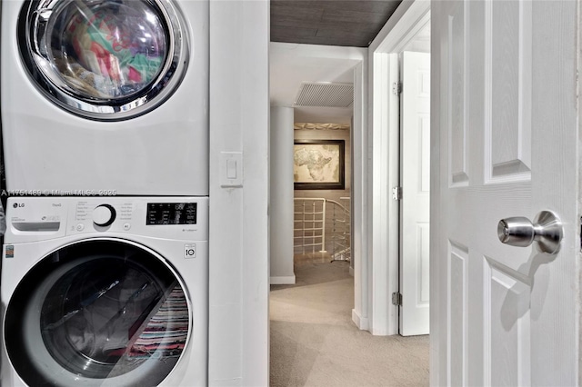 clothes washing area with stacked washing maching and dryer, laundry area, and light colored carpet