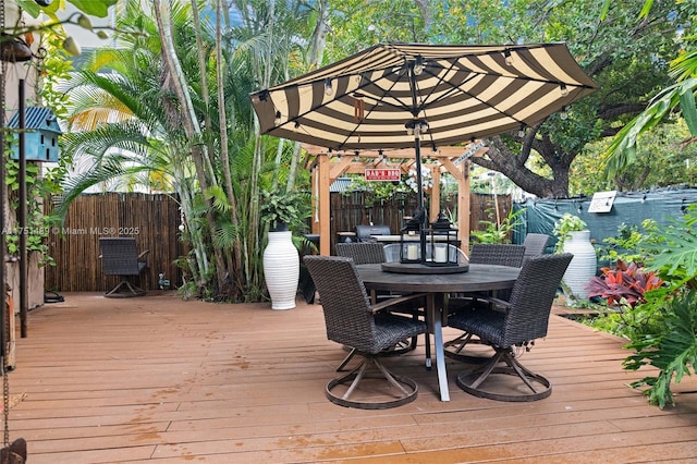 wooden terrace with outdoor dining area and fence