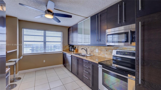 kitchen with light tile patterned floors, tasteful backsplash, appliances with stainless steel finishes, light countertops, and a sink