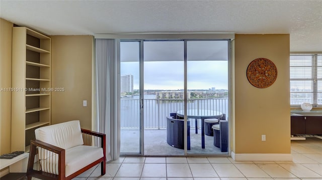 interior space with a water view, light tile patterned floors, a textured ceiling, and a wealth of natural light