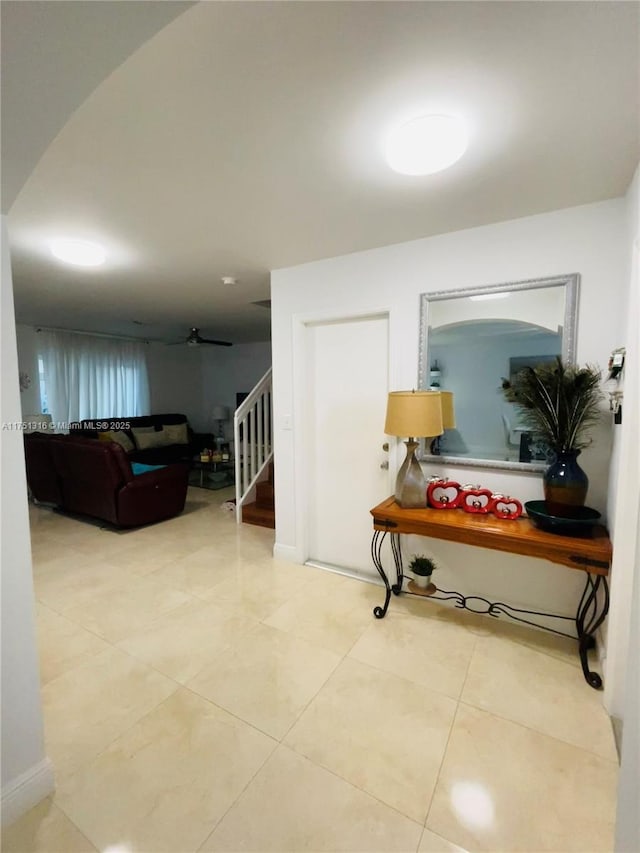 hall featuring stairs and light tile patterned flooring