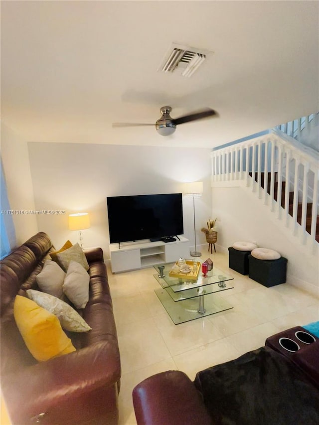 tiled living room with stairs, visible vents, and a ceiling fan