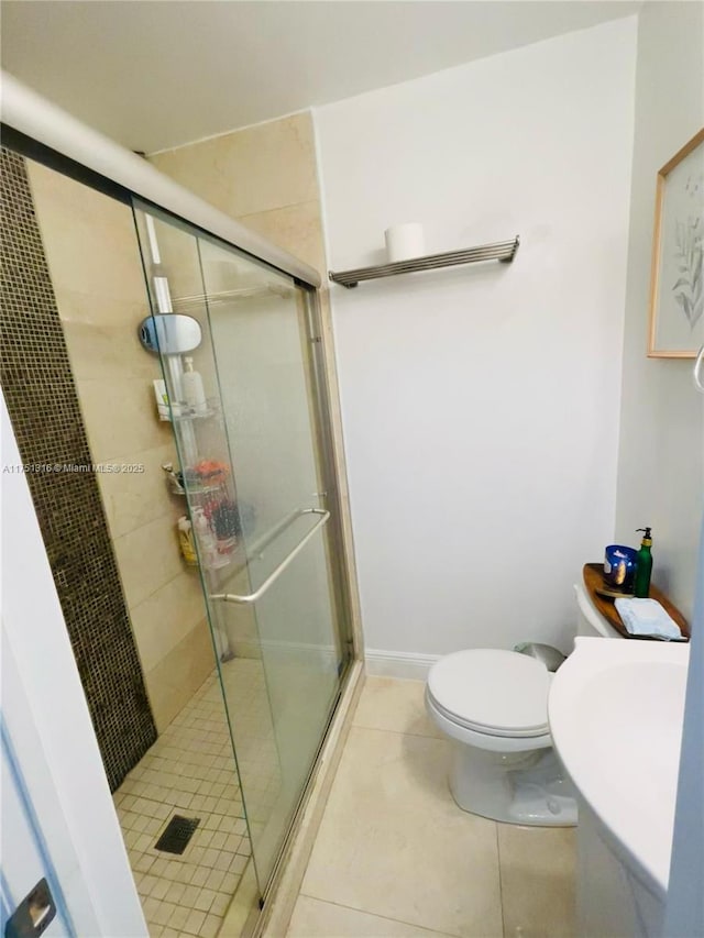 bathroom with a sink, a shower stall, toilet, and tile patterned floors