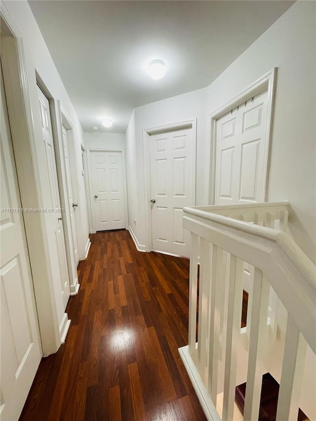 corridor with dark wood-type flooring and baseboards