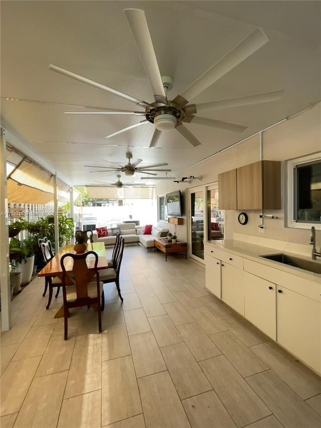 interior space featuring fence, a ceiling fan, outdoor dining area, and a sink