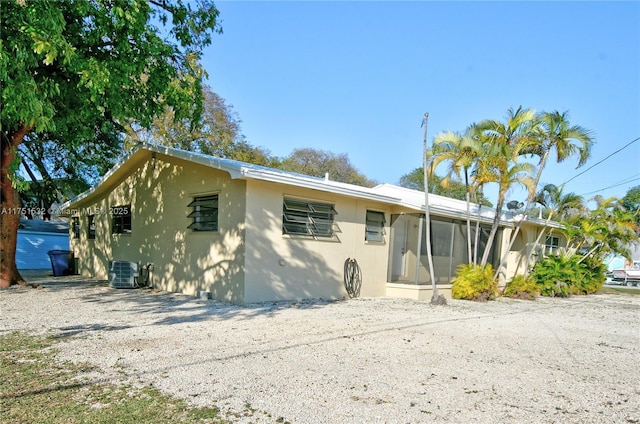 view of front facade featuring central AC unit, a sunroom, and stucco siding