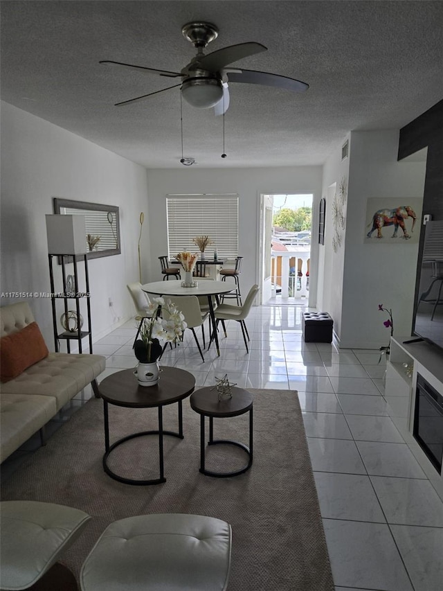 living area with visible vents, ceiling fan, a textured ceiling, and light tile patterned floors