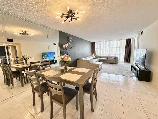 dining room with a textured ceiling, light tile patterned floors, a chandelier, visible vents, and floor to ceiling windows