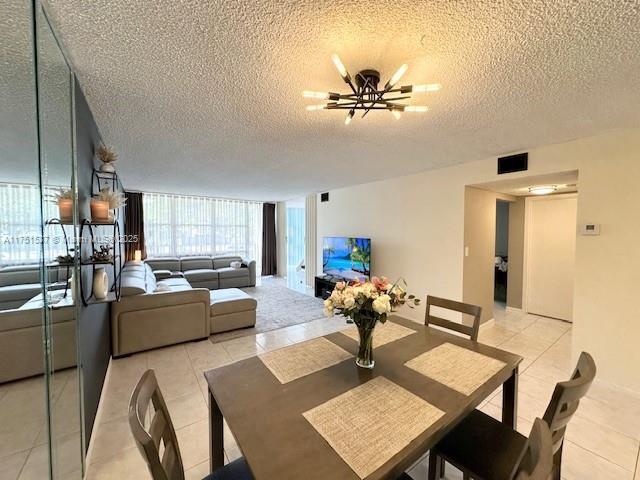 dining area with light tile patterned floors, a textured ceiling, visible vents, and a notable chandelier