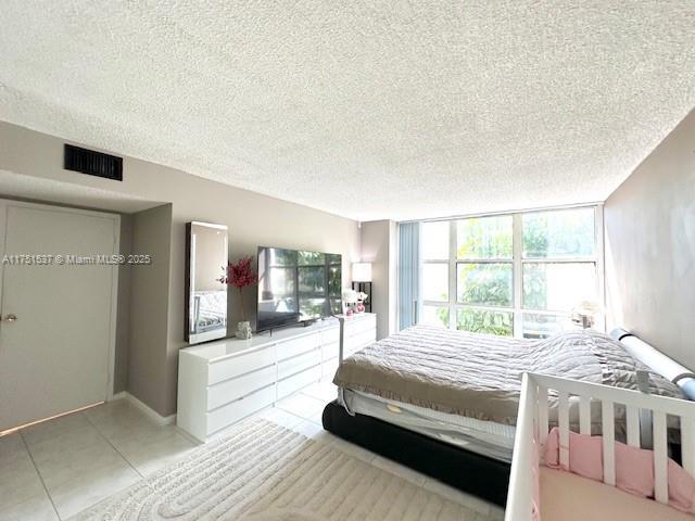 bedroom with light tile patterned floors, visible vents, and a textured ceiling