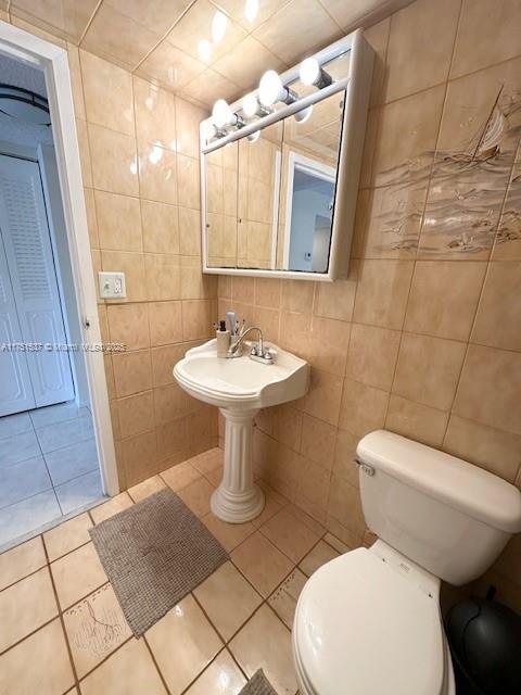 bathroom featuring toilet, tile patterned flooring, and tile walls