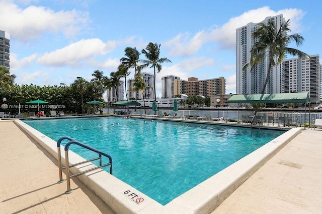 pool with fence, a city view, and a patio