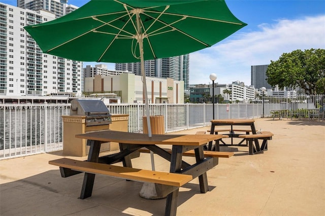 view of patio with a city view, fence, and an outdoor kitchen