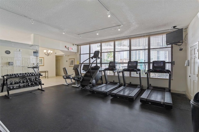 exercise room featuring a textured ceiling and track lighting