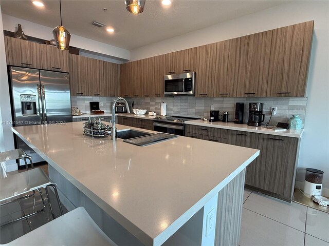 4640 NW 84th Ave Unit 13, Doral, FL 33166 - kitchen featuring stainless steel appliances, modern cabinets, a kitchen bar, decorative backsplash, and a sink