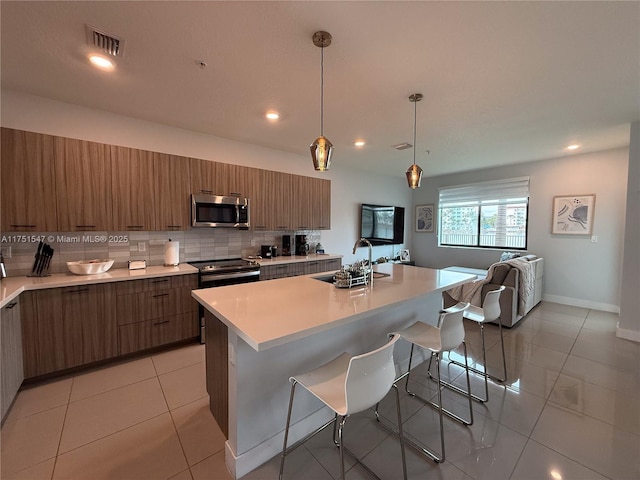 4640 NW 84th Ave Unit 13, Doral, FL 33166 - kitchen with a sink, stainless steel microwave, a kitchen bar, modern cabinets, and light countertops