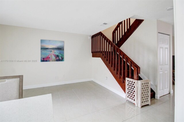 stairway with visible vents, baseboards, and tile patterned floors